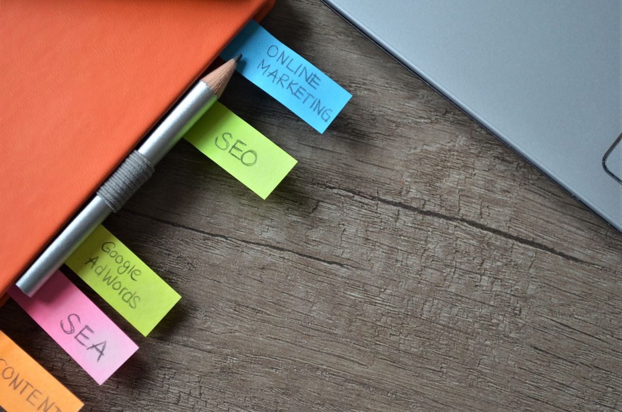 services-02 Gros plan sur un planificateur de stratégie SEO avec des notes adhésives colorées et un crayon sur un carnet.